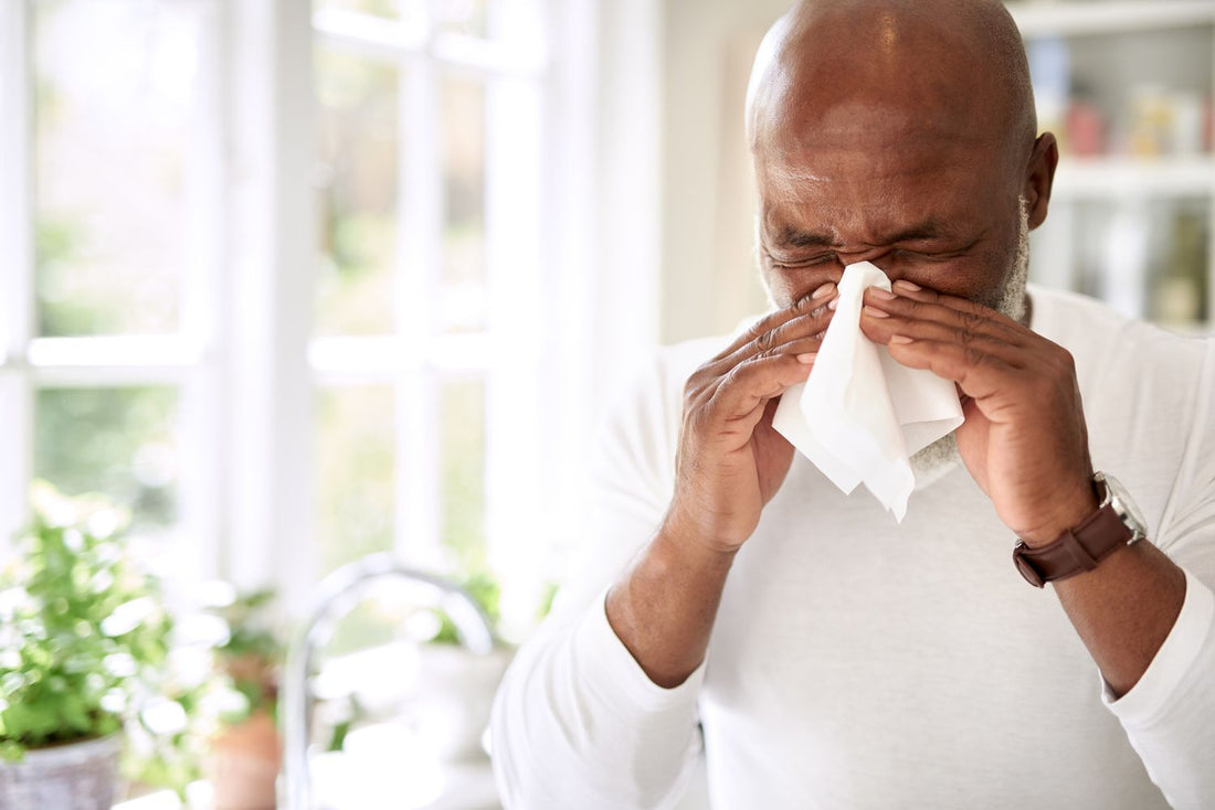 A man sneezing into a tissue due to hayfever
