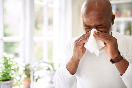 A man sneezing into a tissue due to hayfever